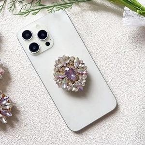 Detail view of a luxury purple crystal flower phone socket on a white mobile phone