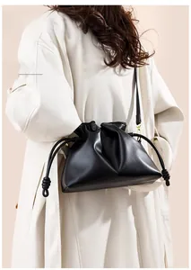 Détail d'un sac seau en cuir noir avec cordon de serrage et finitions dorées chic