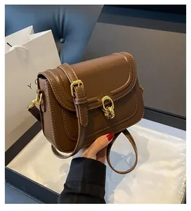 Detail of brown leather bag featuring polished gold hardware buckle and adjustable strap