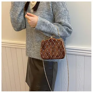 Détail du sac en velours marron avec matelassage losange et fermoir nœud cristal