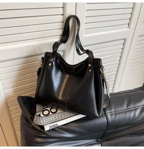 Detail der schwarzen matten Ledertasche mit Goldnieten und gewebtem Schultergurt