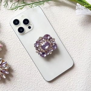 Macro detail of luxury purple crystal and diamond encrusted foldable phone socket grip
