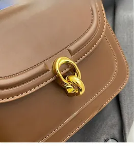 Close-up of vintage golden interlocking metal clasp on high-quality brown leather bag