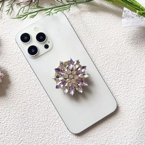 Detailed view of luxury flower phone grip with purple and clear rhinestones on white phone