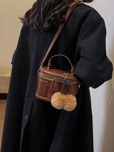 Détail du sac boîte en cuir marron rétro avec charme cerise en peluche et logo doré