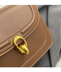 Detail of brown leather bag with golden double-ring buckle and fine stitching