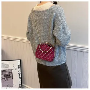 Détail d'un sac en velours bordeaux matelassé avec chaîne porté par un mannequin élégant