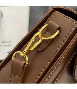 Close-up of premium dark brown leather texture and polished gold spring metal hook