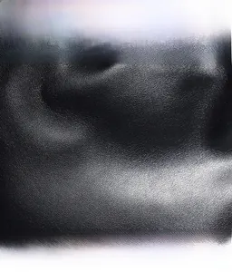 Gros plan d'un sac seau noir avec texture de cuir litchi délicate et brillance naturelle