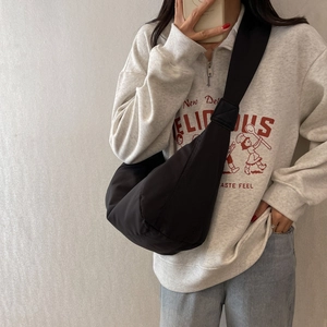 Sac bandoulière en nylon noir en forme de croissant avec large sangle sur un modèle