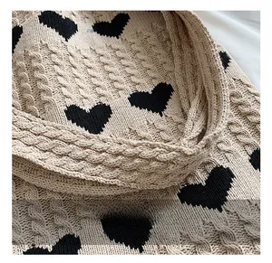 Close-up of khaki cable knit texture and black heart jacquard on a winter tote bag