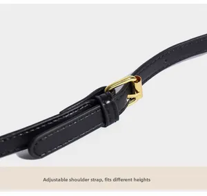 Détail de la bandoulière réglable en cuir noir avec boucle dorée et coutures précises