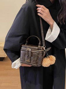 Détail du sac carré vintage marron avec breloque cerise en peluche et zip métallique