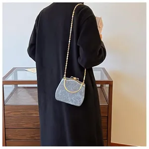 Détail de sac matelassé gris avec fermoir nœud doré et poignée anneau en métal