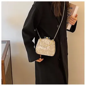 Détail du sac bandoulière en velours beige matelassé avec nœud doré et bandoulière chaîne