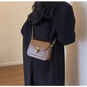 Detailed side view of a brown leather crossbody bag with a gold U-shaped metal lock