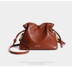 Détail du sac seau en cuir marron avec design plissé et attaches métalliques dorées