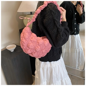 Pink quilted puffy shoulder bag with scrunchie strap detail on a stylish model