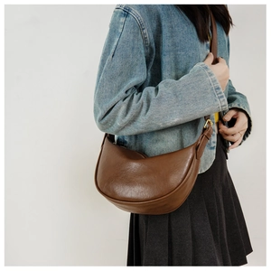 Detail der weichen braunen Mondsichel-Tasche mit breitem Gurt und goldener Schnalle