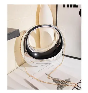 Detail of silver metallic circular cutout handbag with golden chain strap and mirror finish