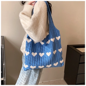 Detail of navy knit tote bag with white heart pattern and thick braided texture on shoulder