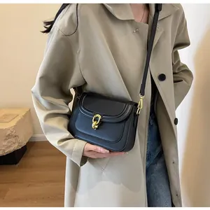 Elegant black PU leather crossbody bag with a gold metal twist lock on a model