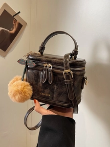 Détail d'un sac à main vintage marron avec finitions dorées et breloque cerise