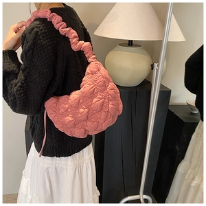 Pink quilted puffer bag featuring pleated texture and ruffled shoulder strap in use