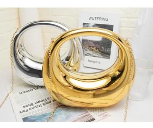 Detail of moon-shaped metallic handbag in gold and silver finish with hollow round handle