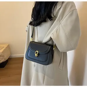 Detail of black crossbody bag with gold horsebit buckle on smooth matte synthetic leather