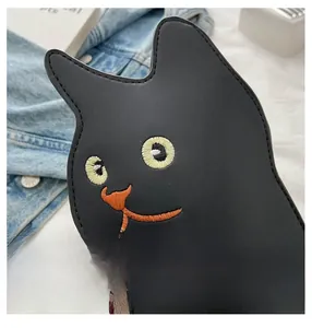 Detailed embroidery of cat facial features on black leather crossbody bag surface