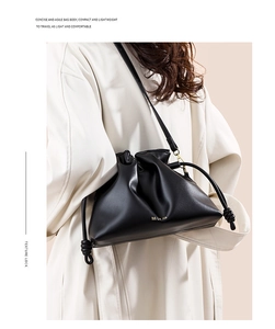 Détail du sac seau nuage noir avec fermeture à cordon et logo doré sur le mannequin