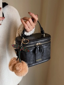 Détail d'une trousse à maquillage noire vintage avec un charmant pendentif cerise