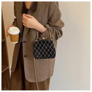 Détail du sac boîte en velours noir avec matelassage blanc et fermoir nœud doré par mannequin