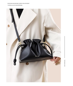 Détail d'un sac seau compact en cuir noir avec cordons et finitions métalliques dorées