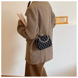 Gros plan d'un sac à main noir matelassé avec poignée dorée porté par un mannequin