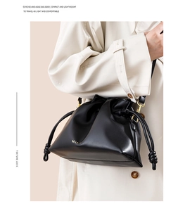 Détail d'un sac seau en cuir noir avec cordon de serrage et crochets métalliques dorés
