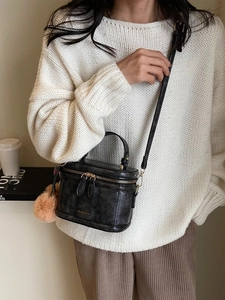 Gros plan du sac cylindrique noir en cuir craquelé vintage avec fermeture éclair dorée