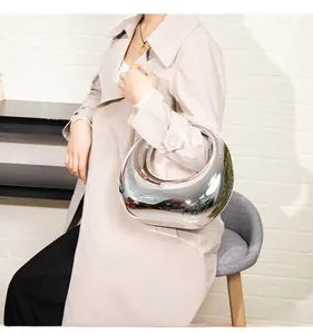 Close-up of a silver metallic hobo bag with sleek curved design held by a model
