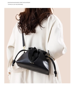 Gros plan du sac seau en cuir noir avec logo doré sur un mannequin en manteau blanc