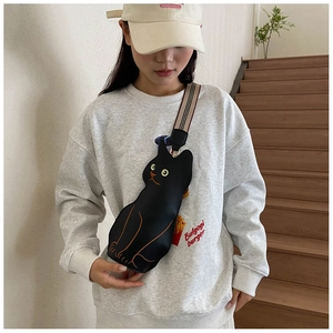 Detail of cute black cat crossbody bag with colorful striped shoulder strap on model