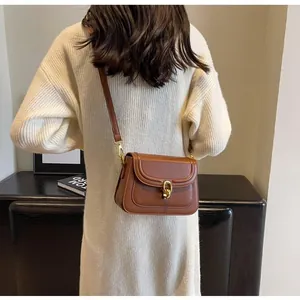 Detail of brown vintage leather crossbody bag with gold metal twist lock and thin strap