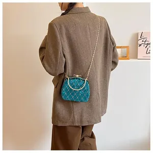 Détail d'un sac boîte en velours bleu sarcelle avec matelassage doré et strass brillants