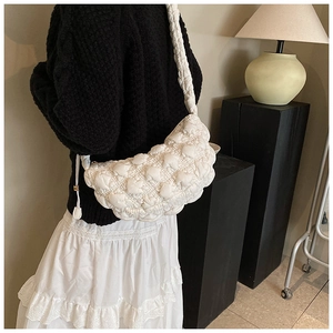 Detailed view of white quilted bubble tote bag worn over shoulder in cozy room