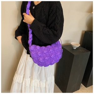 Fashionable purple quilted nylon hobo bag shown on a model with simple minimalist backdrop