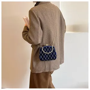 Détail du sac à main en velours bleu matelassé avec poignée en métal doré