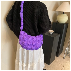 Detail of a purple quilted puffy shoulder bag with square stitching and cloud shape