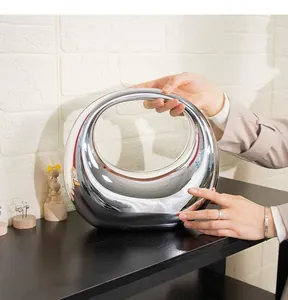 Close-up of a silver acrylic circular handbag with a high-shine mirror finish and hollow center