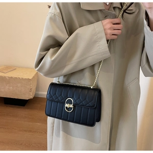 Detail einer schwarzen Stepptasche mit goldener Kette und metallischem Ovalverschluss