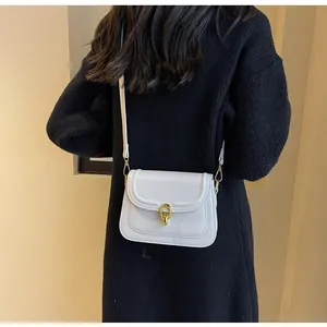 Detail view of white glossy patent leather bag with a golden oval rotating clasp lock